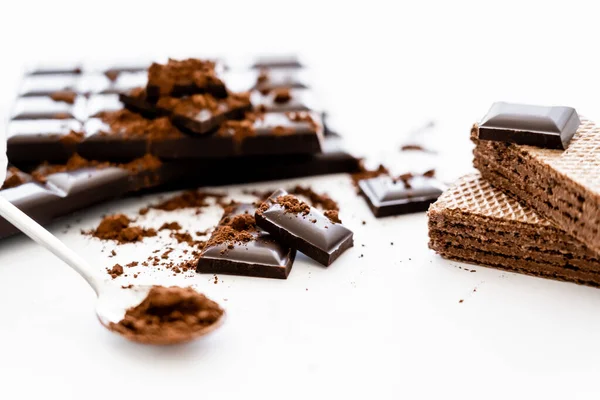 Nahaufnahme von Schokolade, Waffeln und verschwommenem Kakao in einem Löffel auf weißem Hintergrund — Stockfoto