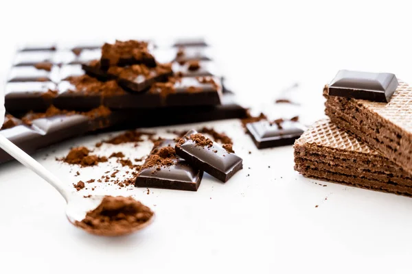 Close up view of chocolate, waffles and blurred cocoa in spoon on white background — Stockfoto