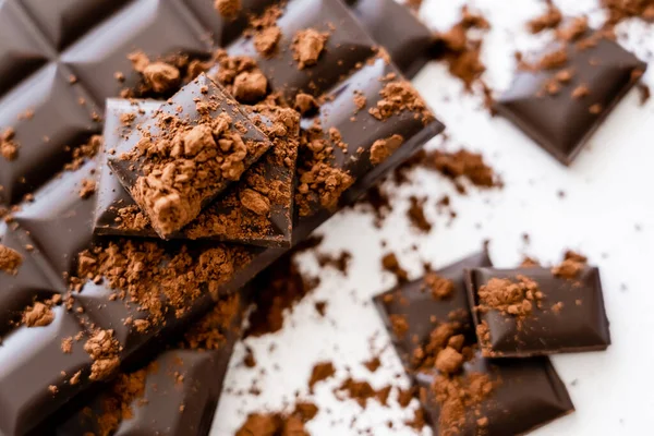 Top view of cocoa on dark chocolate bars on white background — Stock Photo