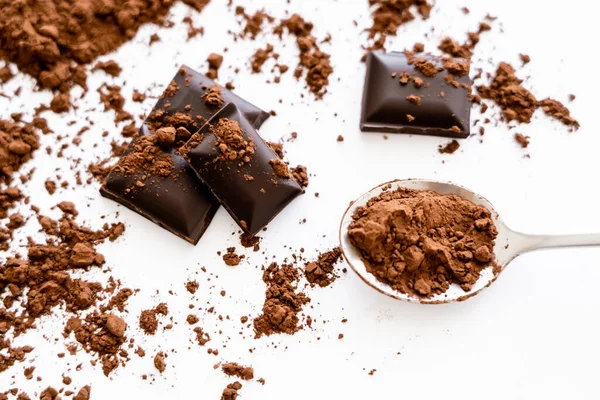 Vista superior de cacau na colher perto de chocolate no fundo branco — Fotografia de Stock