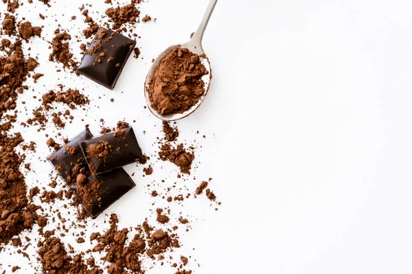 Top view of cocoa in spoon near dark chocolate pieces on white background with copy space — стоковое фото