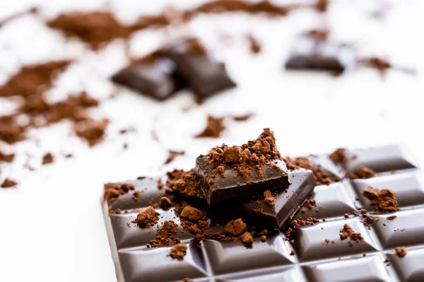 Vista de cerca del cacao seco en polvo sobre chocolate marrón sobre fondo blanco - foto de stock