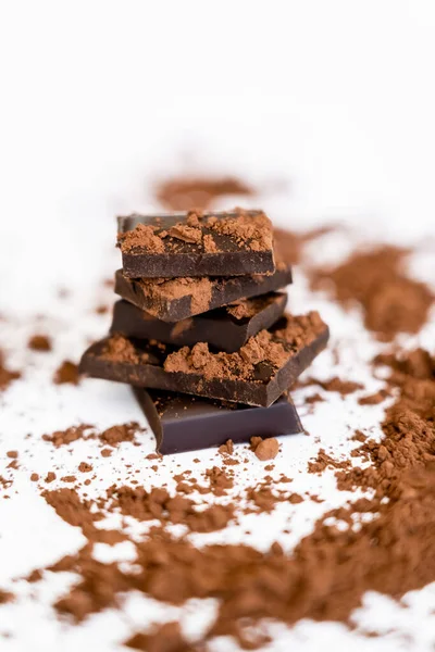 Close up vista de cacau desfocado perto de peças de chocolate escuro no fundo branco — Fotografia de Stock