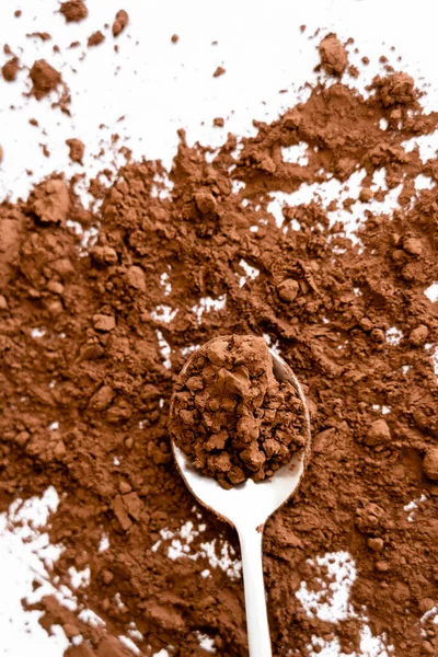 Vue de dessus de la poudre de cacao naturel sur cuillère sur fond blanc — Photo de stock