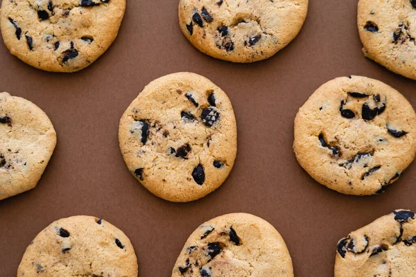 Top view of cookies with chocolate chips on brown background — стоковое фото