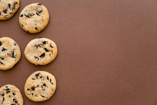Draufsicht auf Kekse mit Schokolade auf braunem Hintergrund mit Kopierraum — Stockfoto