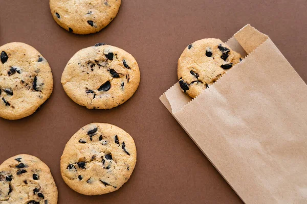 Vista superior de las cookies y paquete artesanal sobre fondo marrón - foto de stock