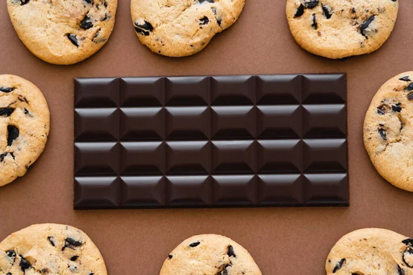 Top view of chocolate bar in frame from cookies on brown background — Fotografia de Stock