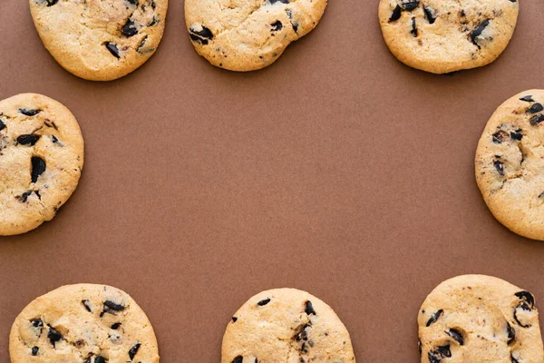 Vue du dessus du cadre à partir de biscuits avec des pépites de chocolat sur fond brun — Photo de stock