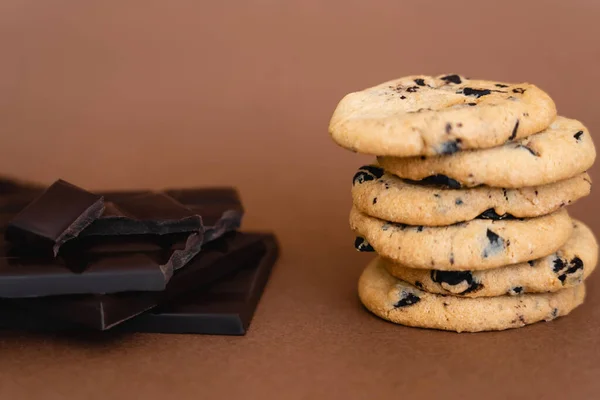 Close up view of cookies and dark chocolate bars on brown background — стоковое фото