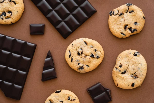 Top view of cookies and dark chocolate on brown background — Foto stock