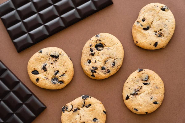 Vista superior de barras de chocolate y galletas sobre fondo marrón - foto de stock