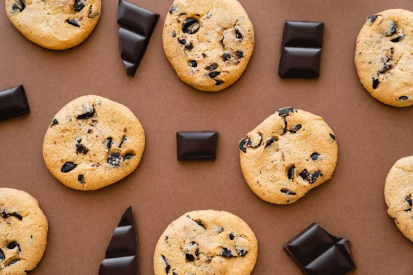 Vue du dessus des morceaux de chocolat près des biscuits sur fond brun — Photo de stock