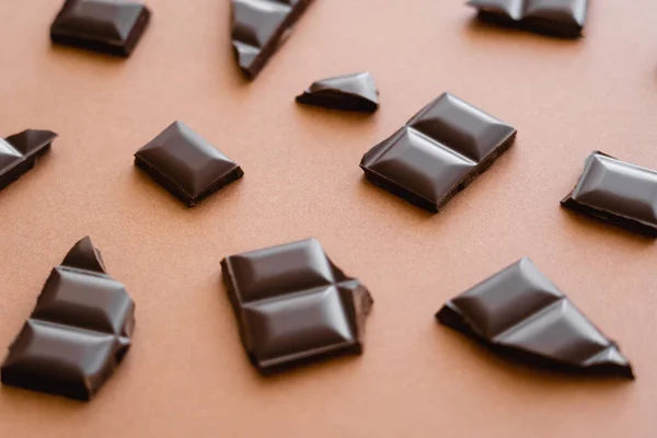 Close up view of pieces of dark chocolate on brown background — Stock Photo