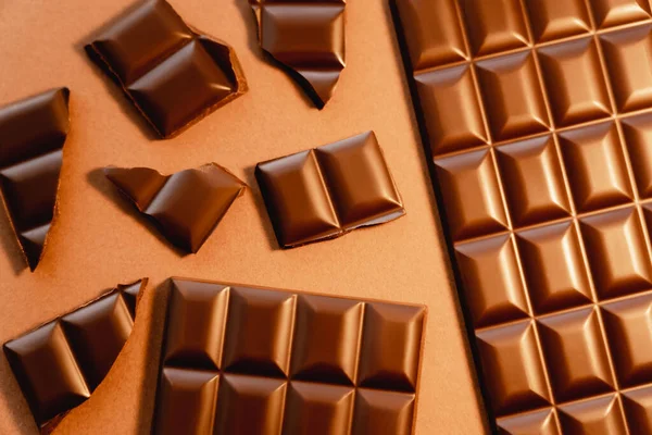Вид сверху натурального молочного шоколада на коричневом фоне — стоковое фото