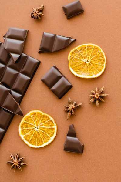 Top view of dry orange slice, chocolate and anise on brown background — Photo de stock