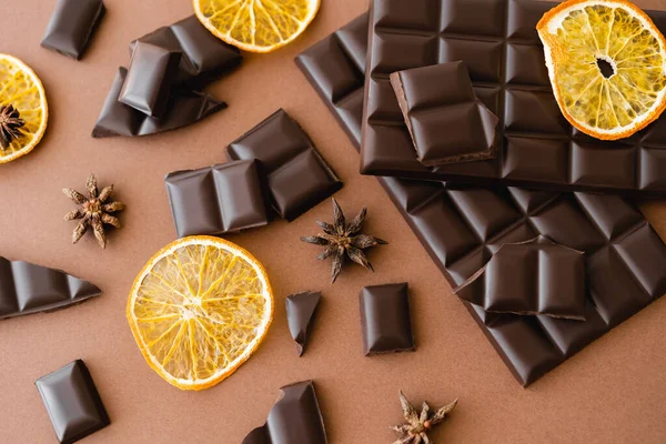 Vista dall'alto di fetta di arancia secca, anice e cioccolato su sfondo marrone — Foto stock