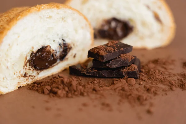 Close up view of croissant near chocolate pieces and cocoa on brown background — Photo de stock