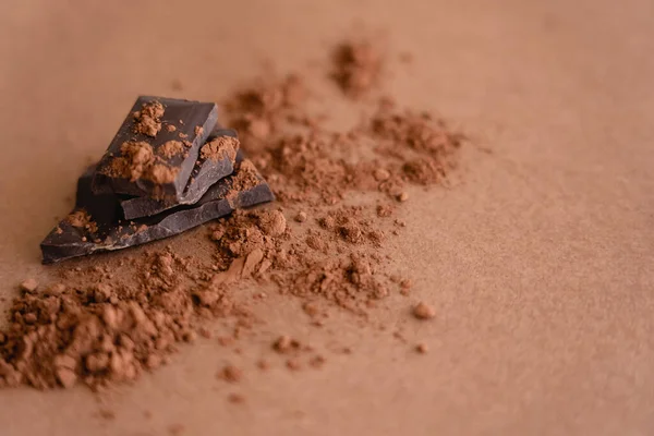 Vista da vicino di cioccolato fondente e cacao in polvere su sfondo marrone con spazio copia — Foto stock