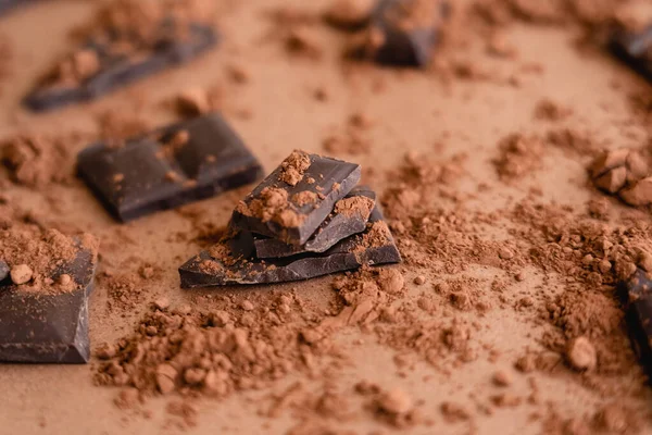 Nahaufnahme von Kakaopulver auf Schokoladenstücken auf braunem Hintergrund — Stockfoto