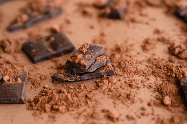 Close up view of cocoa powder on chocolate pieces on brown background — Photo de stock