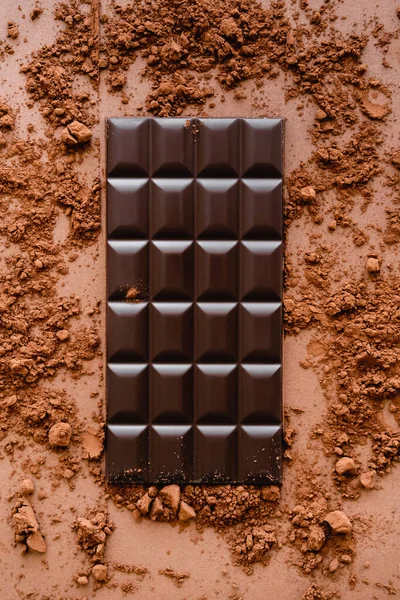 Top view of dark chocolate bar and cocoa on brown background — Stock Photo