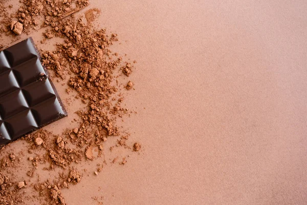 Top view of chocolate bar and dry cocoa on brown background with copy space — Stock Photo