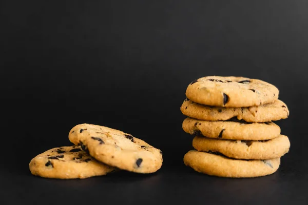 Close up view of cookies with chocolate chips on black background — Photo de stock