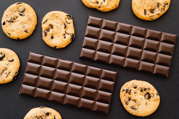 Top view of cookies and chocolate bars on black background — Stock Photo