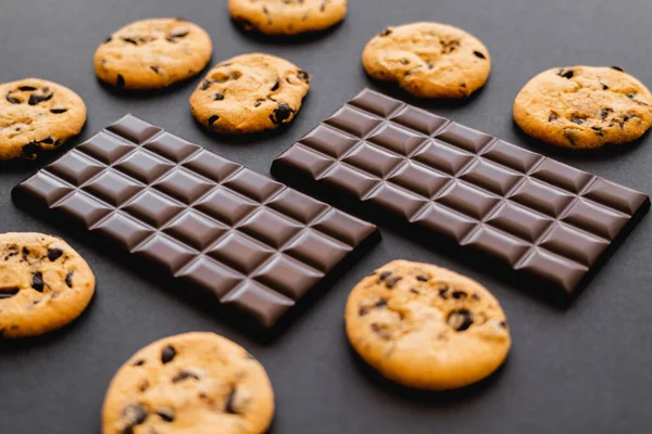 Barres de chocolat noir près des biscuits sur fond noir — Photo de stock