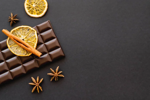 Top view of cinnamon, anise and orange slice on chocolate on black background — Photo de stock