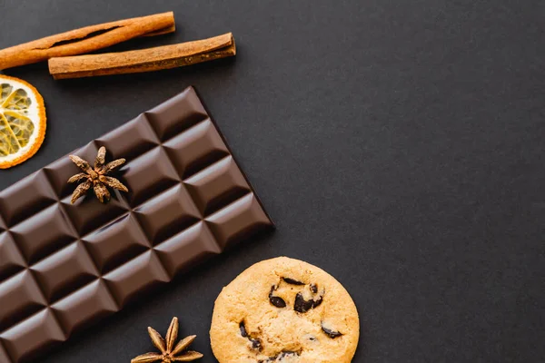 Top view of cookie, chocolate and natural spices on black background — Stock Photo
