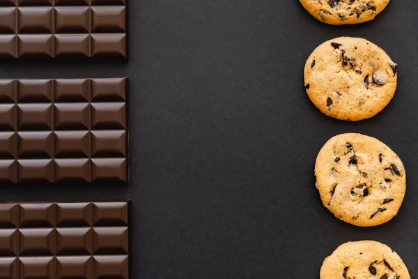 Flat lay with chocolate bars and cookies on black background — Stockfoto