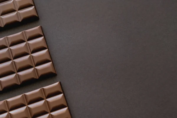 Draufsicht auf dunkle Schokoladentafeln auf schwarzer Oberfläche mit Kopierraum — Stockfoto