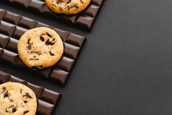 Top view of tasty cookies on chocolate bars on black background — Stock Photo