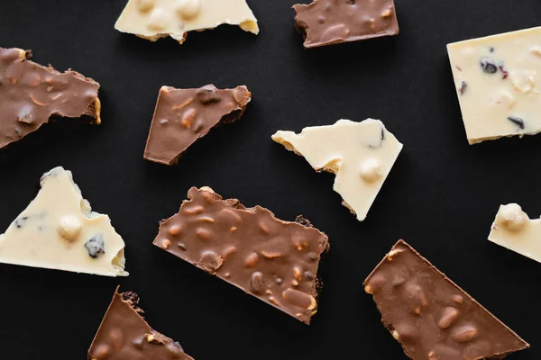 Top view of pieces of milk and white chocolate on black background — Stock Photo