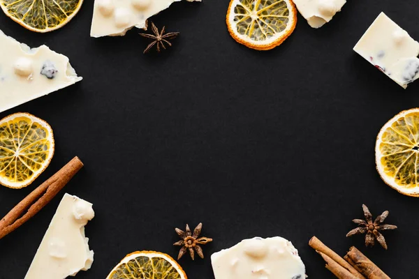 Vue de dessus du cadre à partir de chocolat blanc, tranches d'orange sèche et épices sur fond noir — Photo de stock