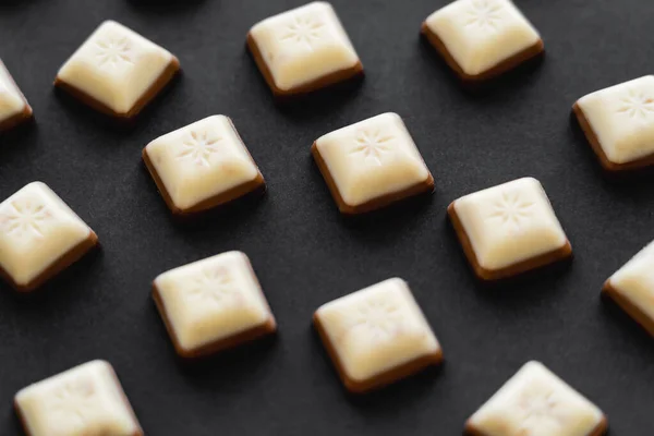 Close-up vista de branco e pedaços de chocolate com leite no fundo preto — Fotografia de Stock