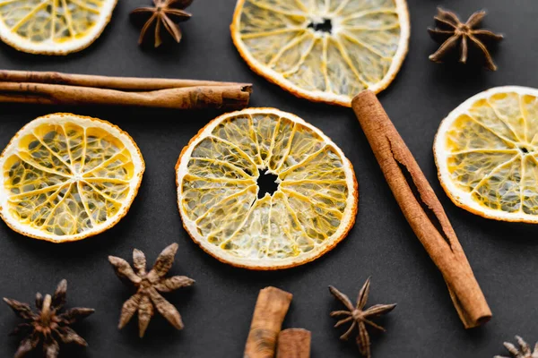 Vista de perto de paus de canela, anis e fatias de laranja seca no fundo preto — Fotografia de Stock