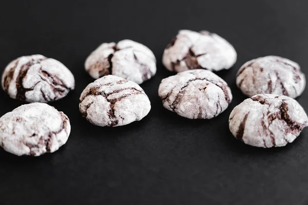 Close up view of biscuits with powdered sugar on black surface — Stock Photo