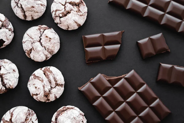 Верхний вид печенья с сахарной пудрой и шоколадом на черном фоне — стоковое фото