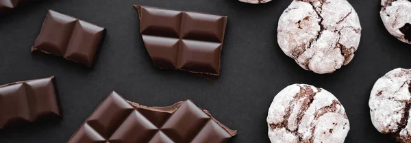 Top view of chocolate near biscuits on black background, banner — Stock Photo