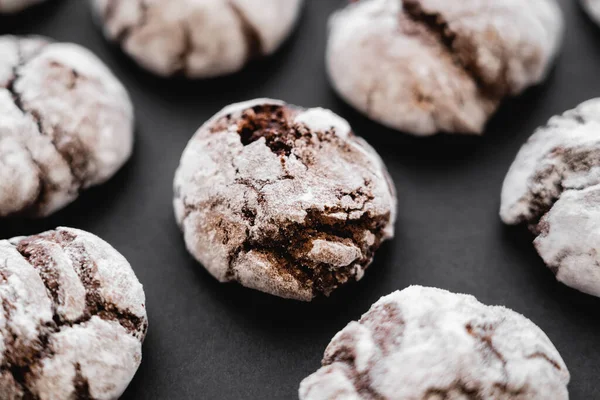 Close up view of baked biscuits with powdered sugar on black surface — Photo de stock