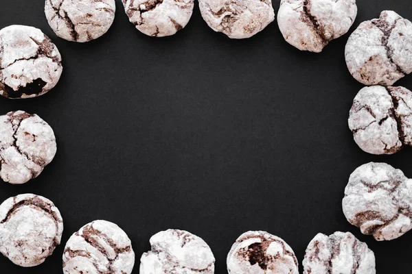 Top view of frame from biscuits with powdered sugar on black background - foto de stock