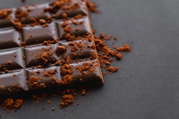 Close up view of cocoa powder on chocolate on black background — Fotografia de Stock