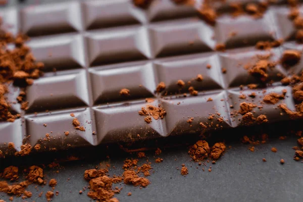 Close up view of natural cocoa on chocolate bar on black background — Fotografia de Stock