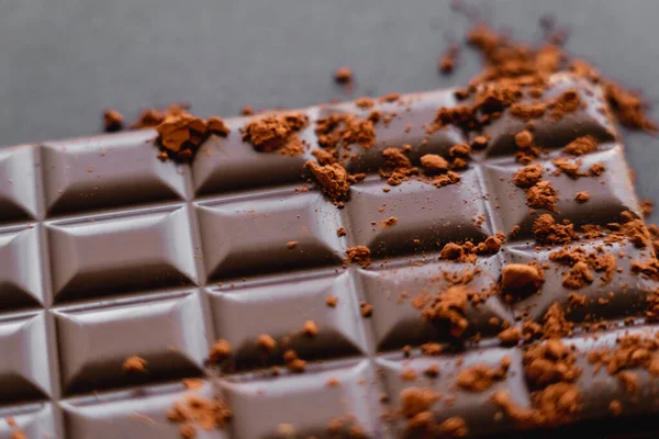 Close up view of dry cocoa powder on natural chocolate on black background — Fotografia de Stock