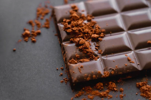 Close up view of dry cocoa on chocolate bar on black background — Foto stock