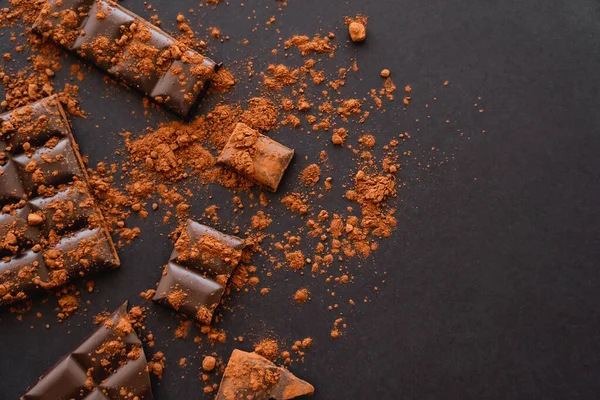 Top view of natural cocoa powder and chocolate on black background — Fotografia de Stock