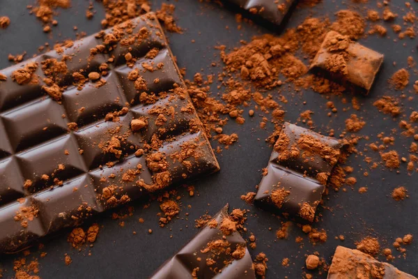 Top view of dark chocolate and coca powder on black background — Stock Photo